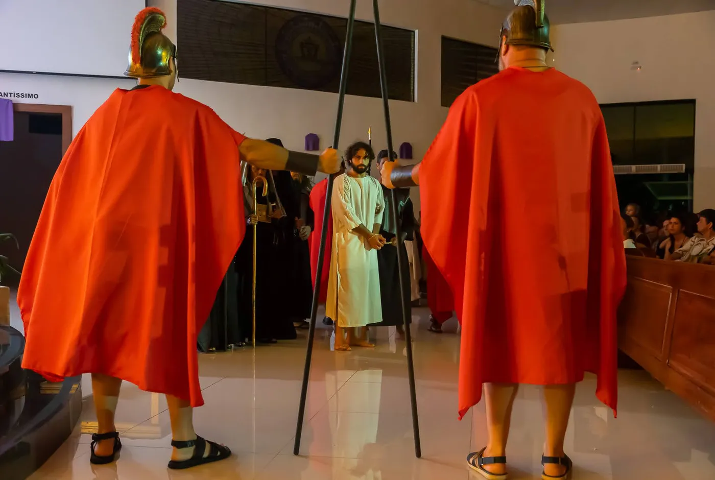 Two Roman soldiers backlit in red, Christ bound in white between them